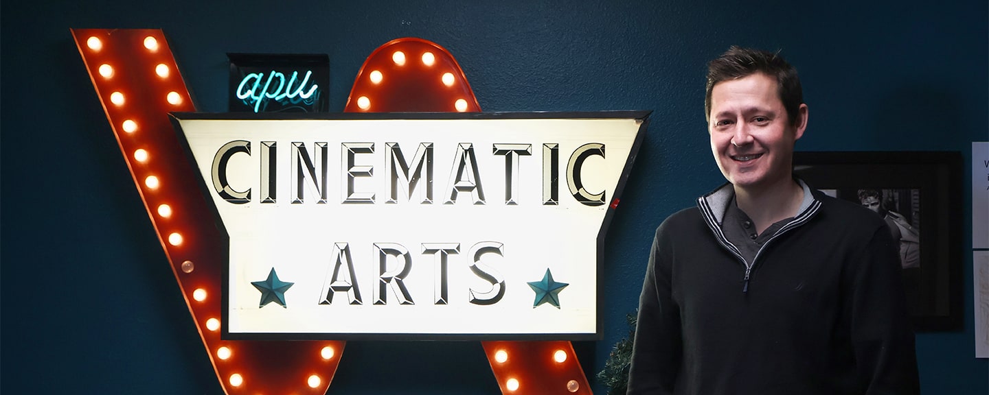 Zach smiling next to the Cinematic Art's logo