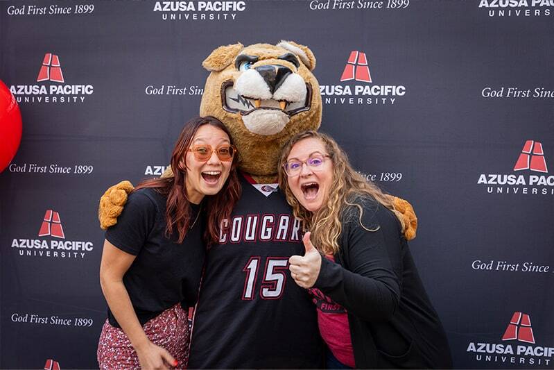 students smiling and hugging mascot cougar