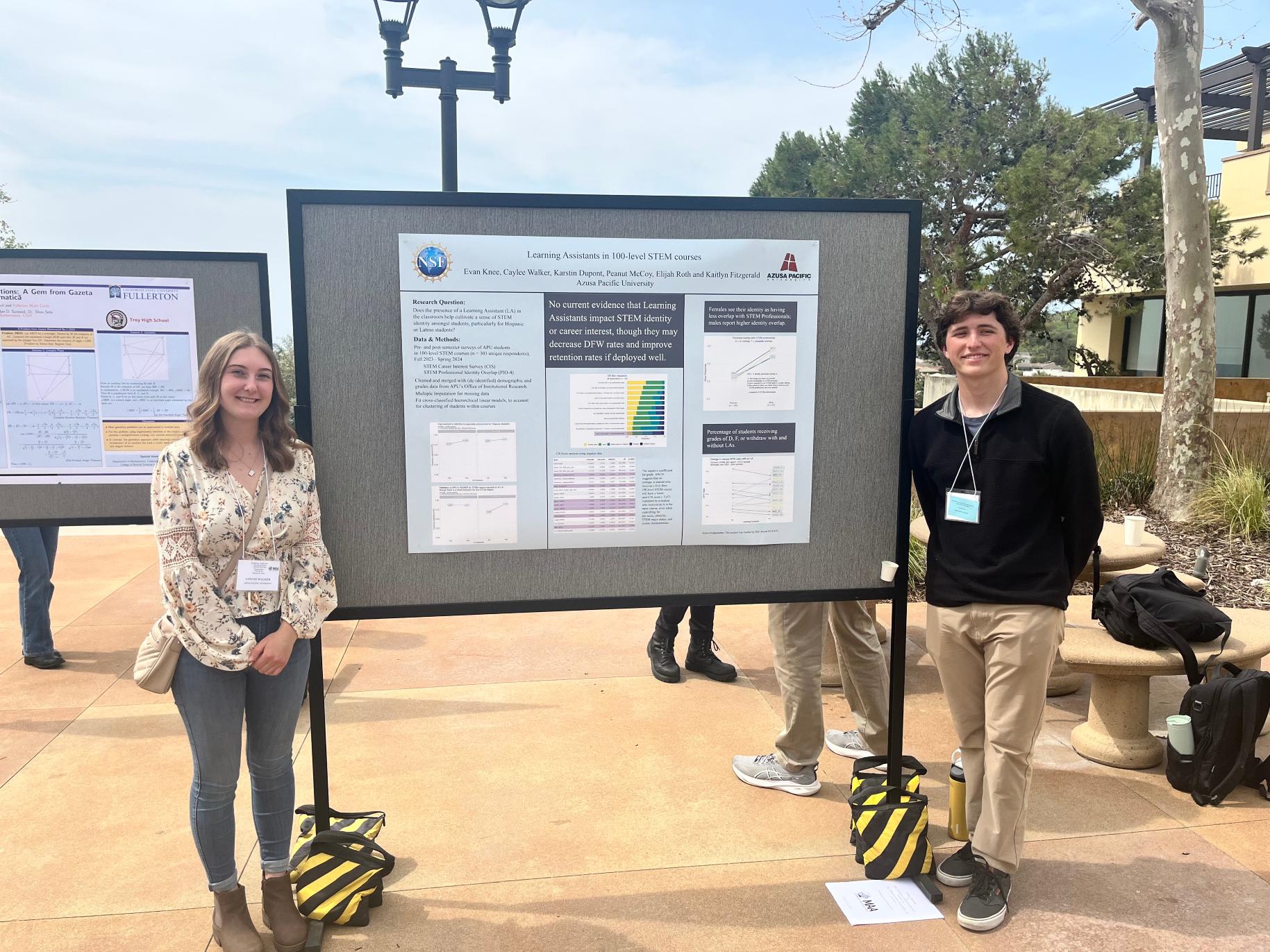 Caylee and Evan stand with a poster of their research at a conference.