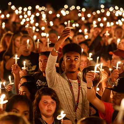 apu students holding lit candles during event at apu