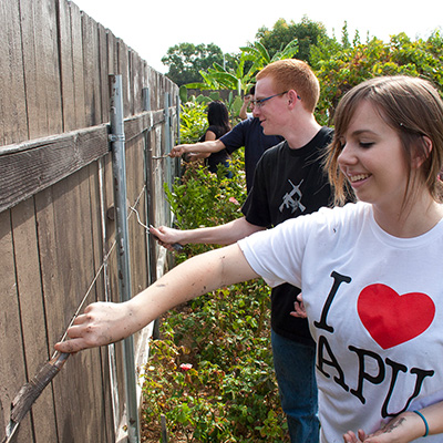 apu students smiling and painting a fence