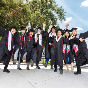 students celebrating graduation wearing cap and gown