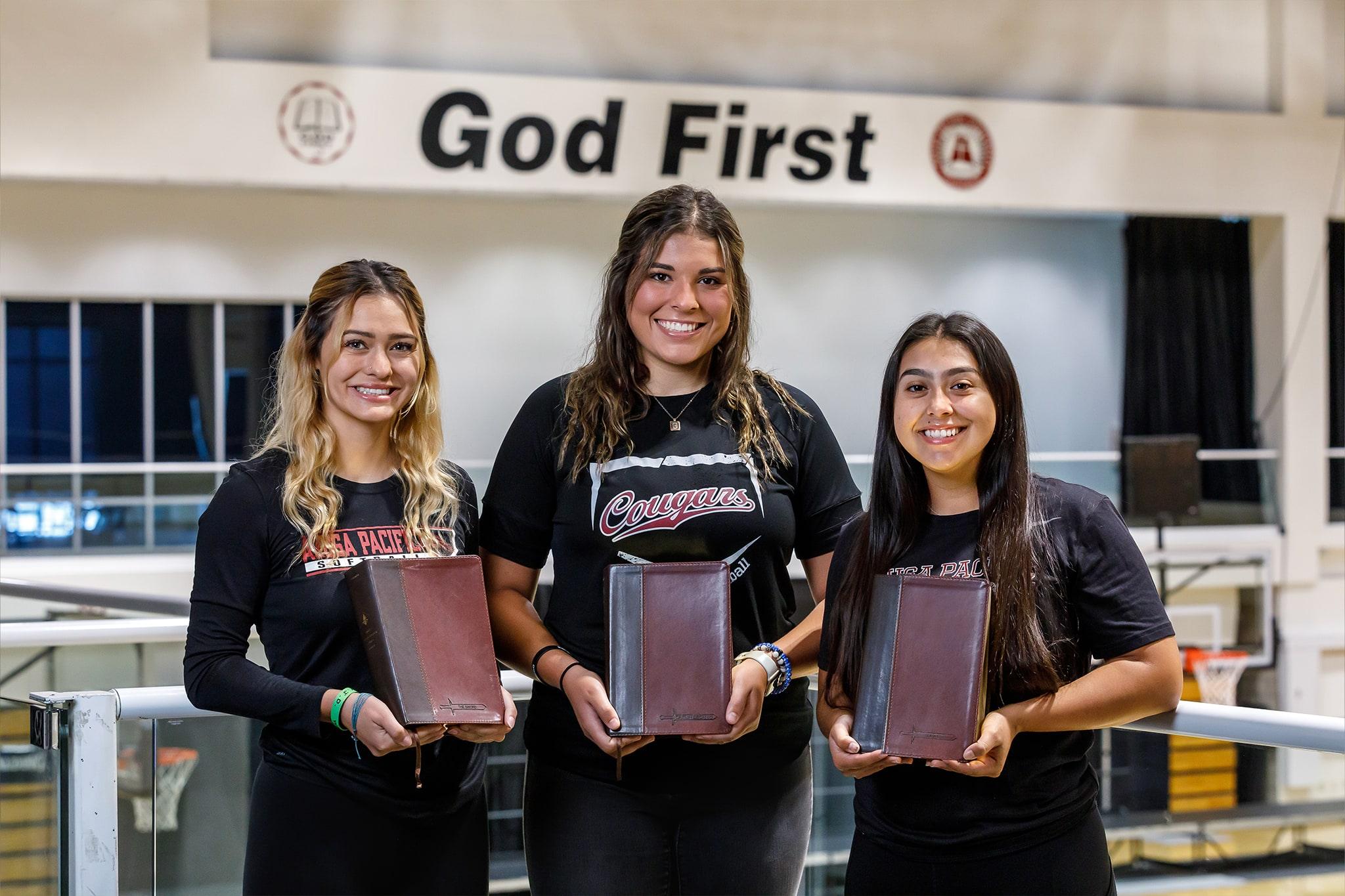 students holding the bible and smiling for the picture