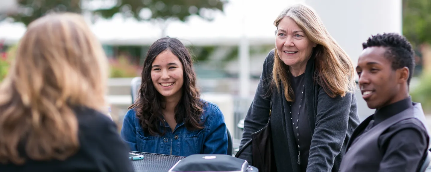 students talking and smiling with their professor