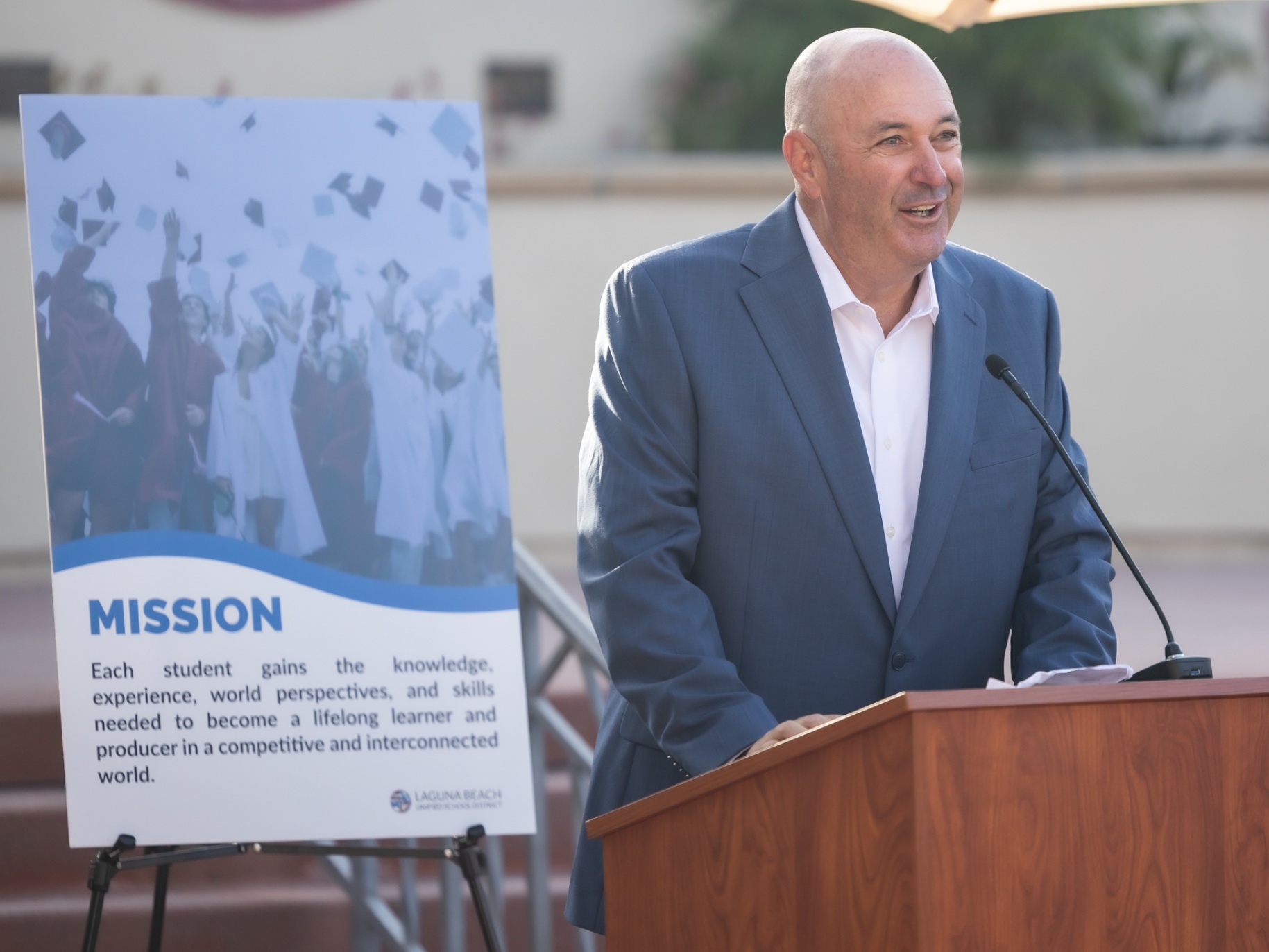 Austin speaking at a podium for an event with the LBUSD mission statement behind him.