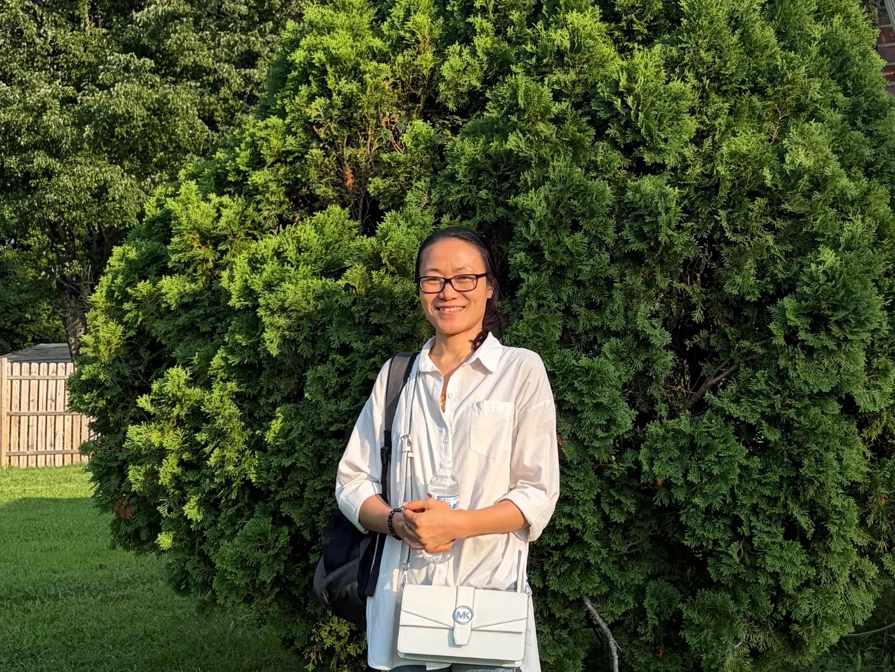 Student smiling, trees in background