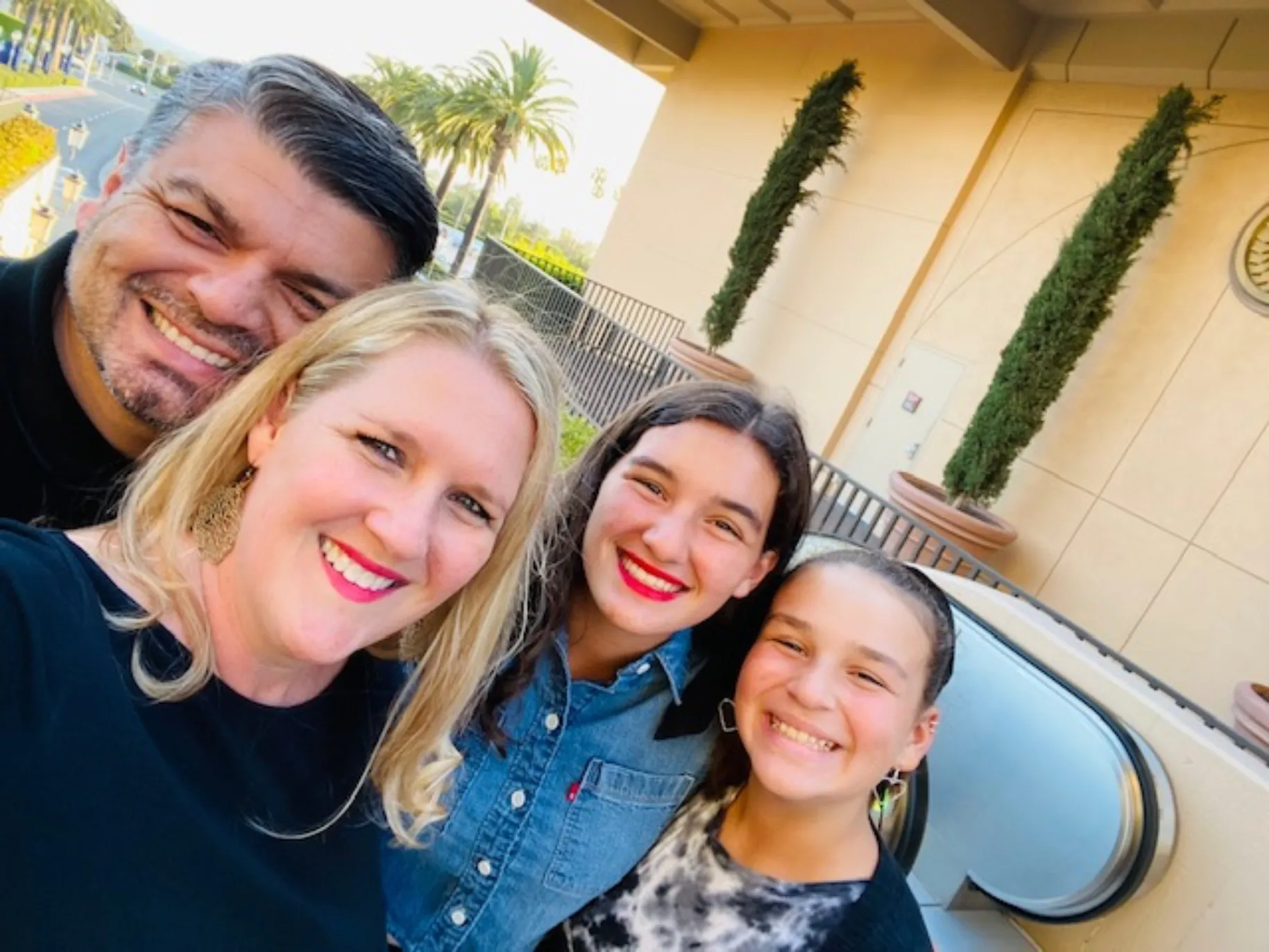 Angela Robles taking a selfie outside with her husband and daughters.