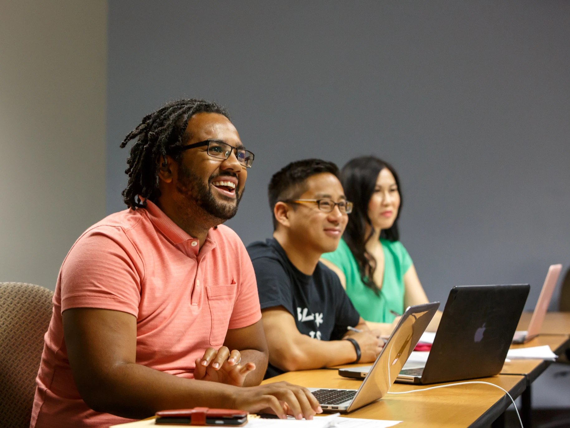 Three students work on laptops in an educational leadership class.