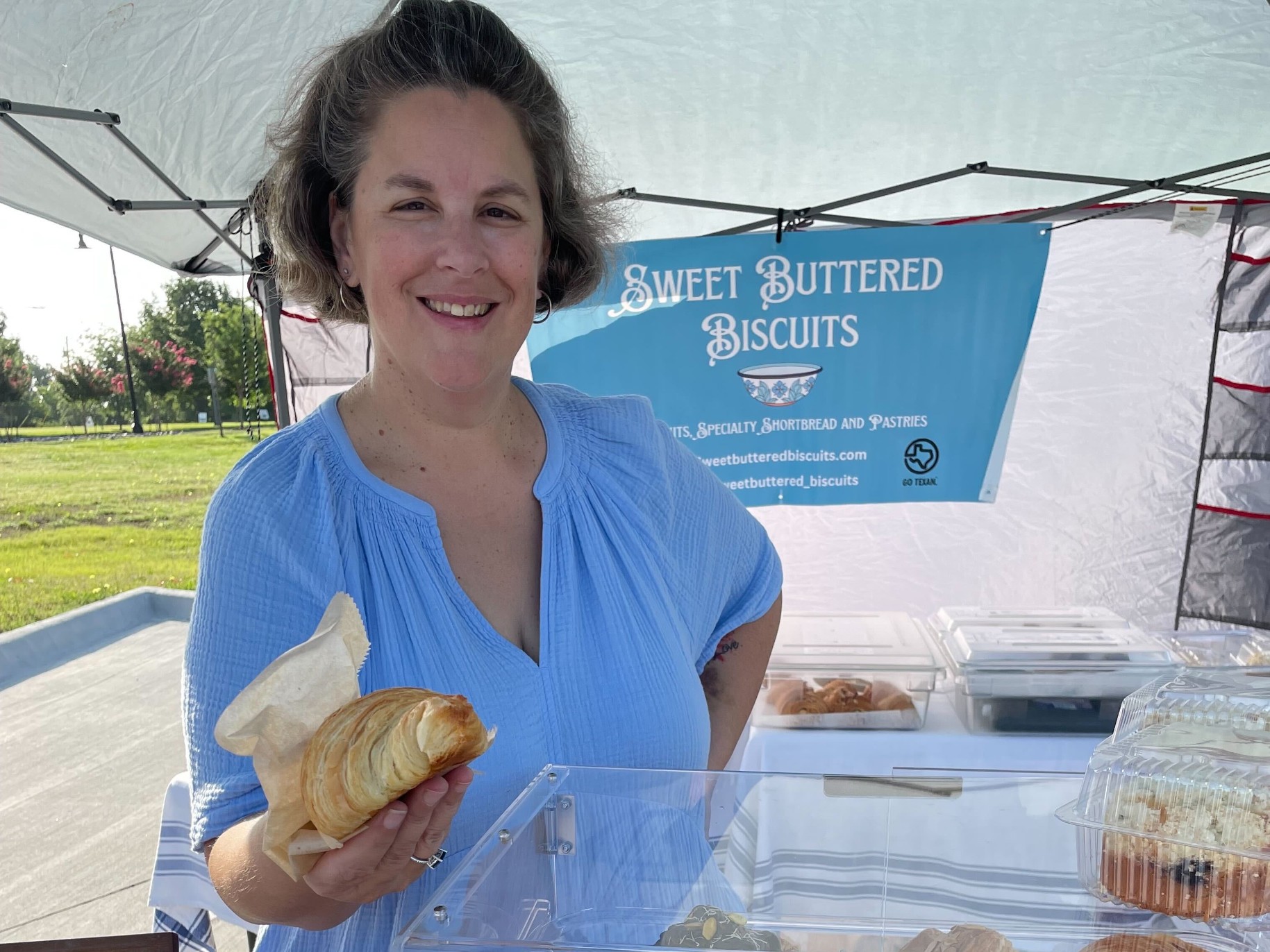 Jenna smiles while holding a pastry at a farmers market