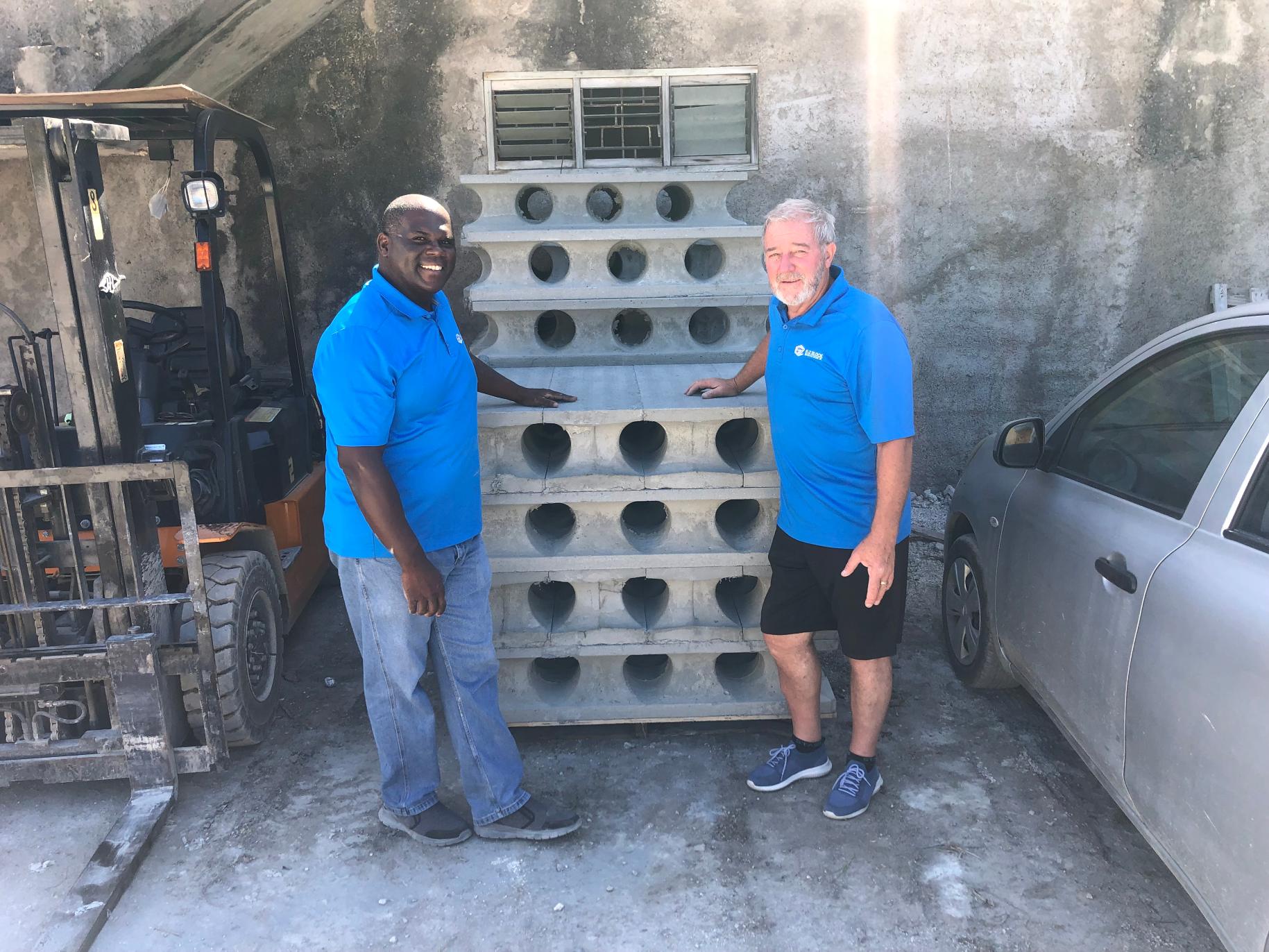 Jerrold stands with his business partner in front of E-Z Blocks building materials.