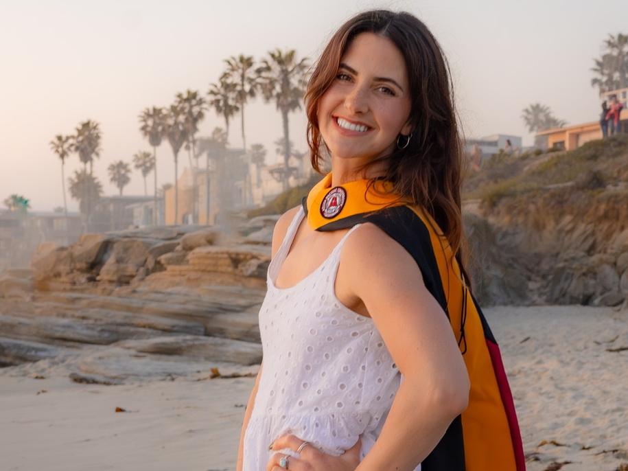 Meghan Matas smiles outside in her graduation regalia.