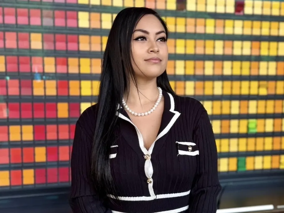 Monica Rodriguez stands for a professional picture in front of a colorful background.