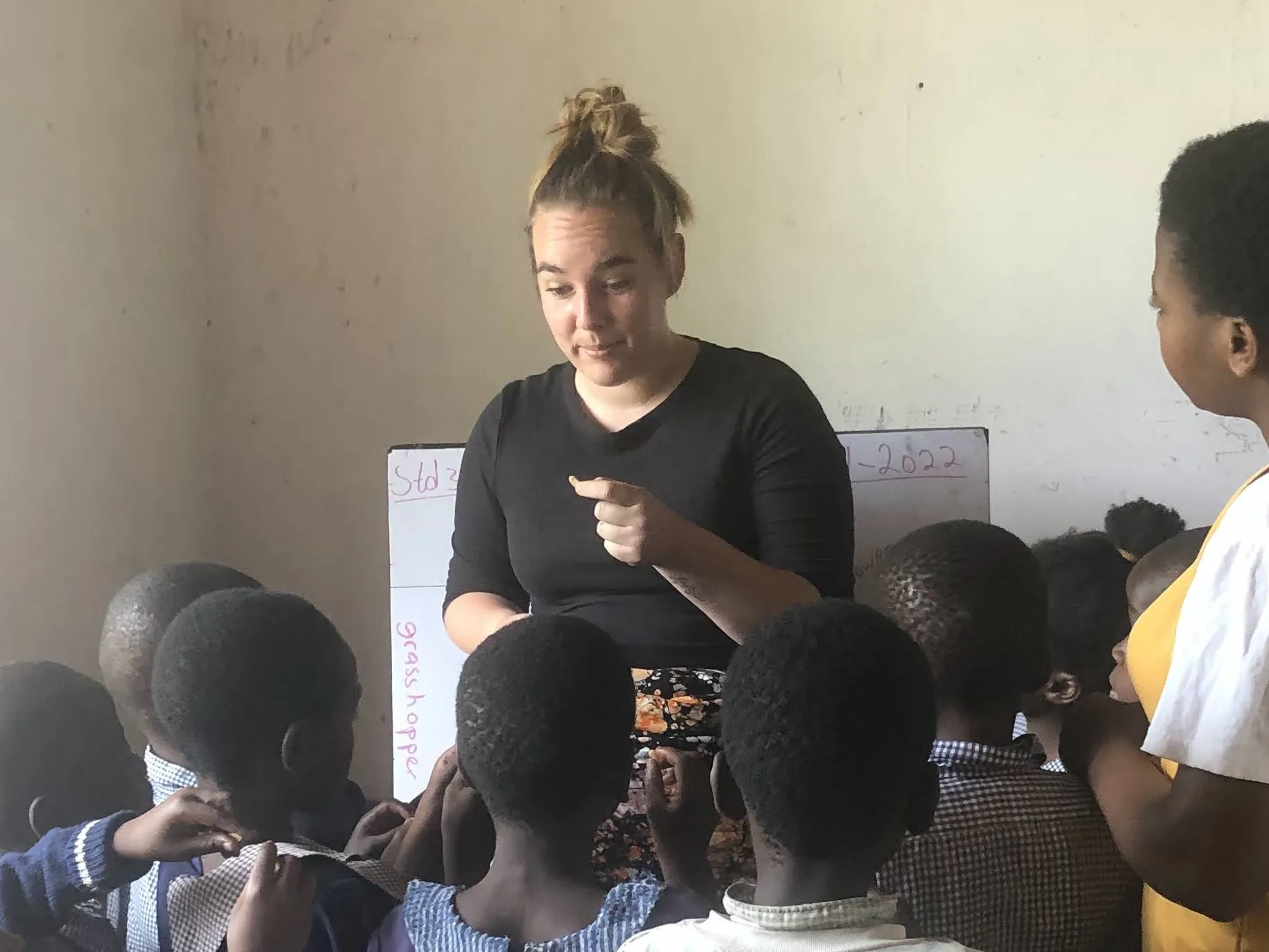 Ady with a group of children surrounding her as she teaches about a seed