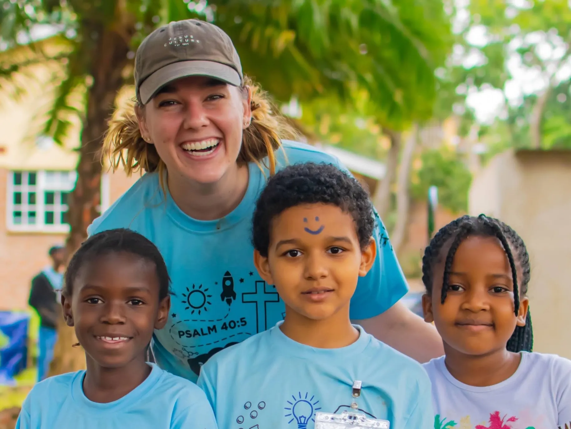Ady smiling with three young children at school
