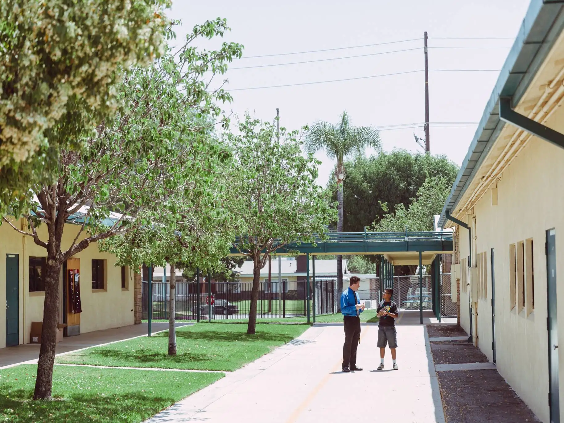A teacher and student stand outside of a school.