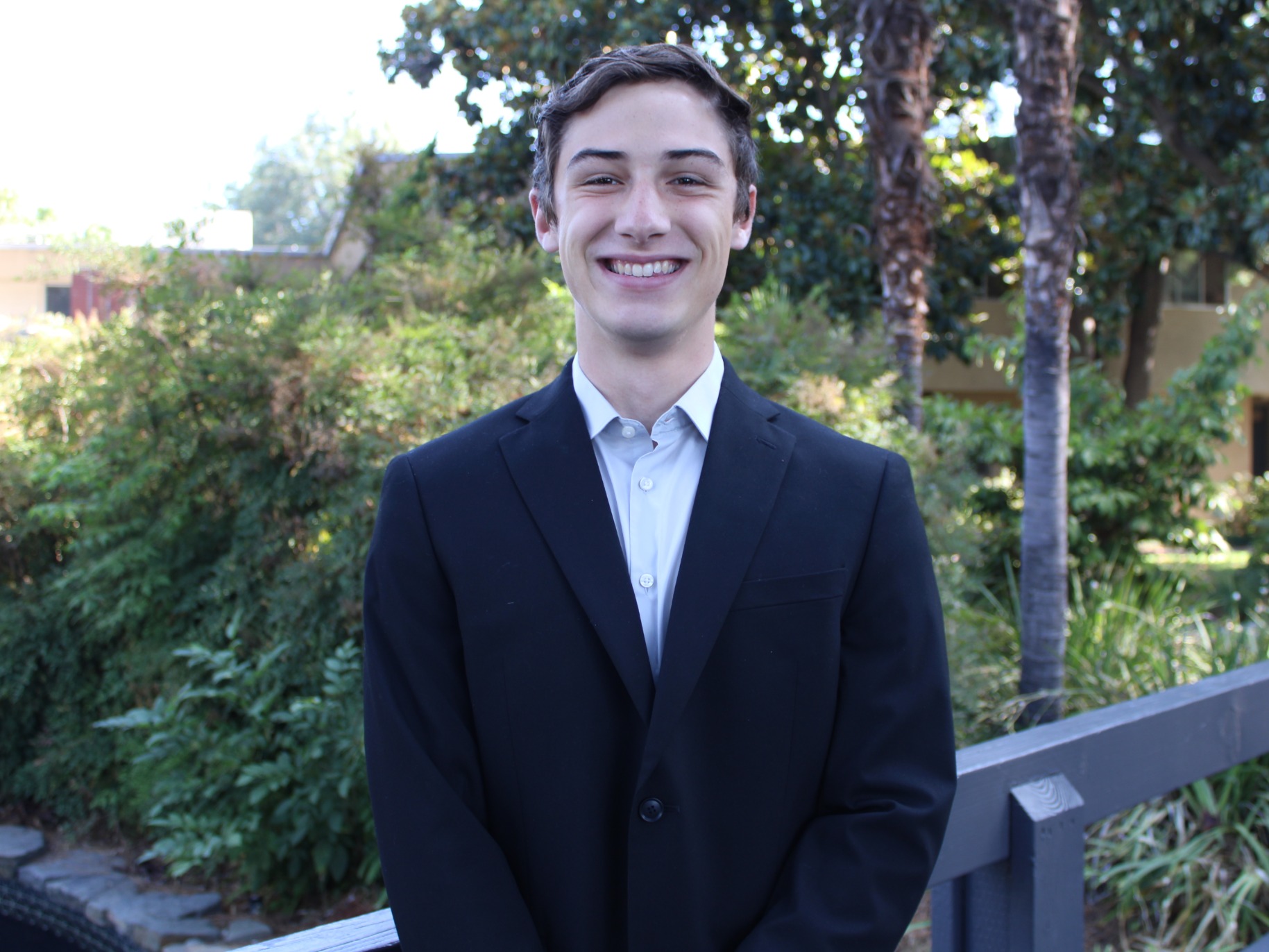 Student stands smiling by bridge 