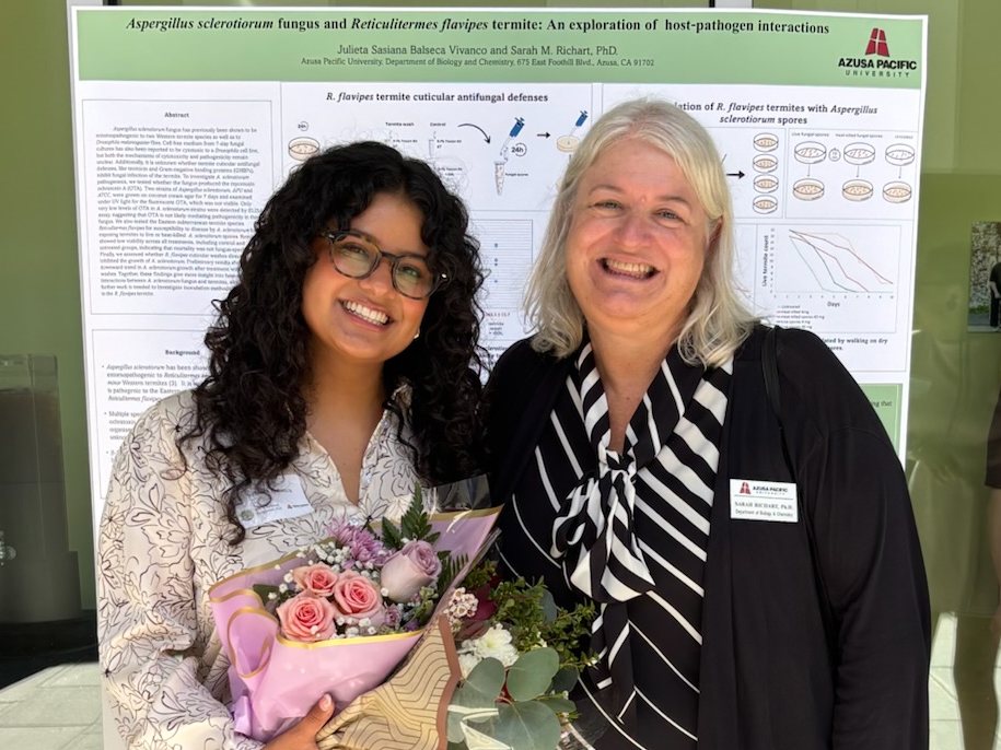 Sasiana Balseca and Sarah Richart stand in front of a research poster.