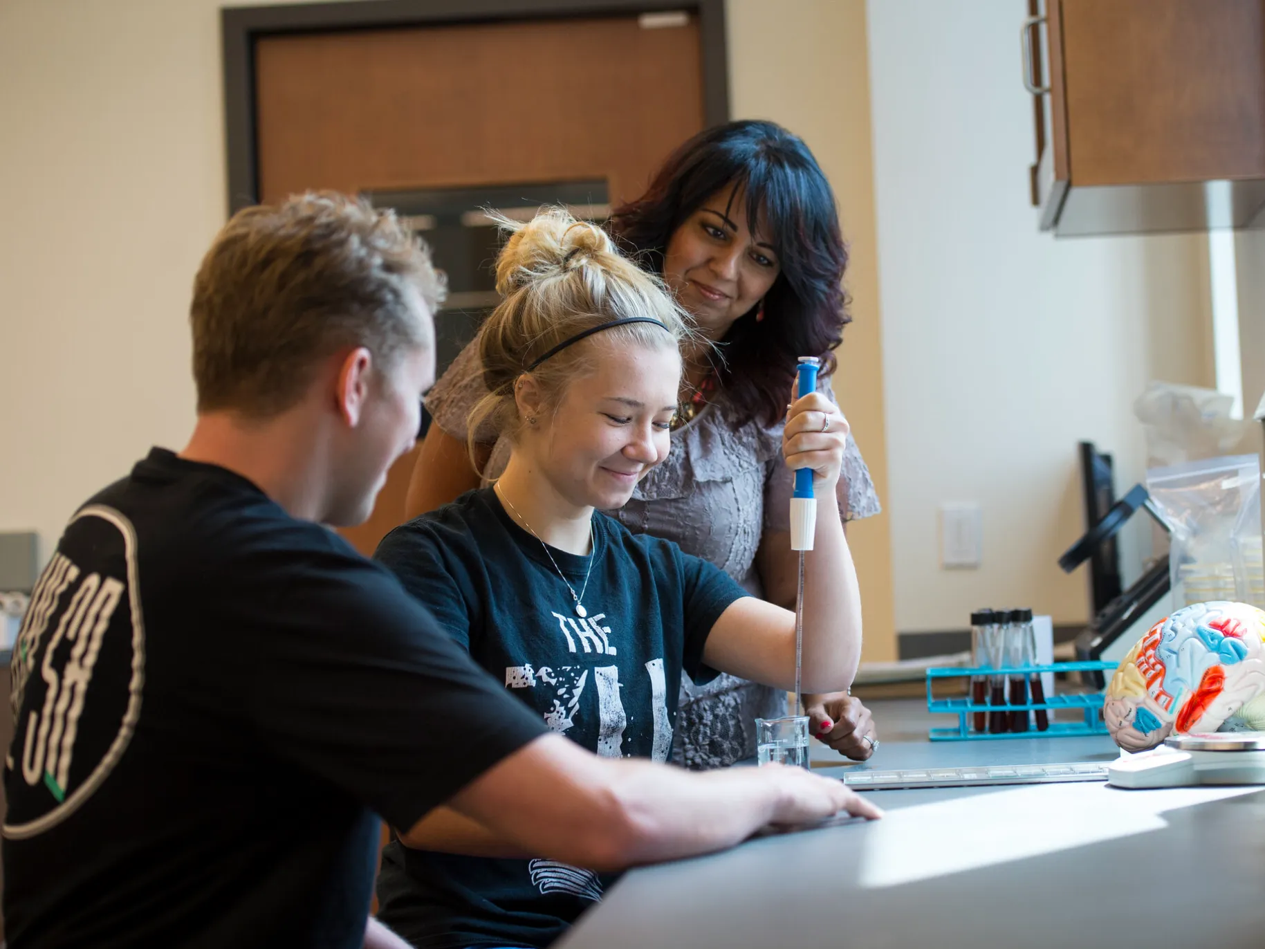 Two students and professor working on lab project.