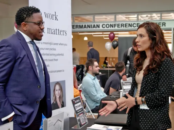 a man and woman wearing suits and speaking during an business event at apu