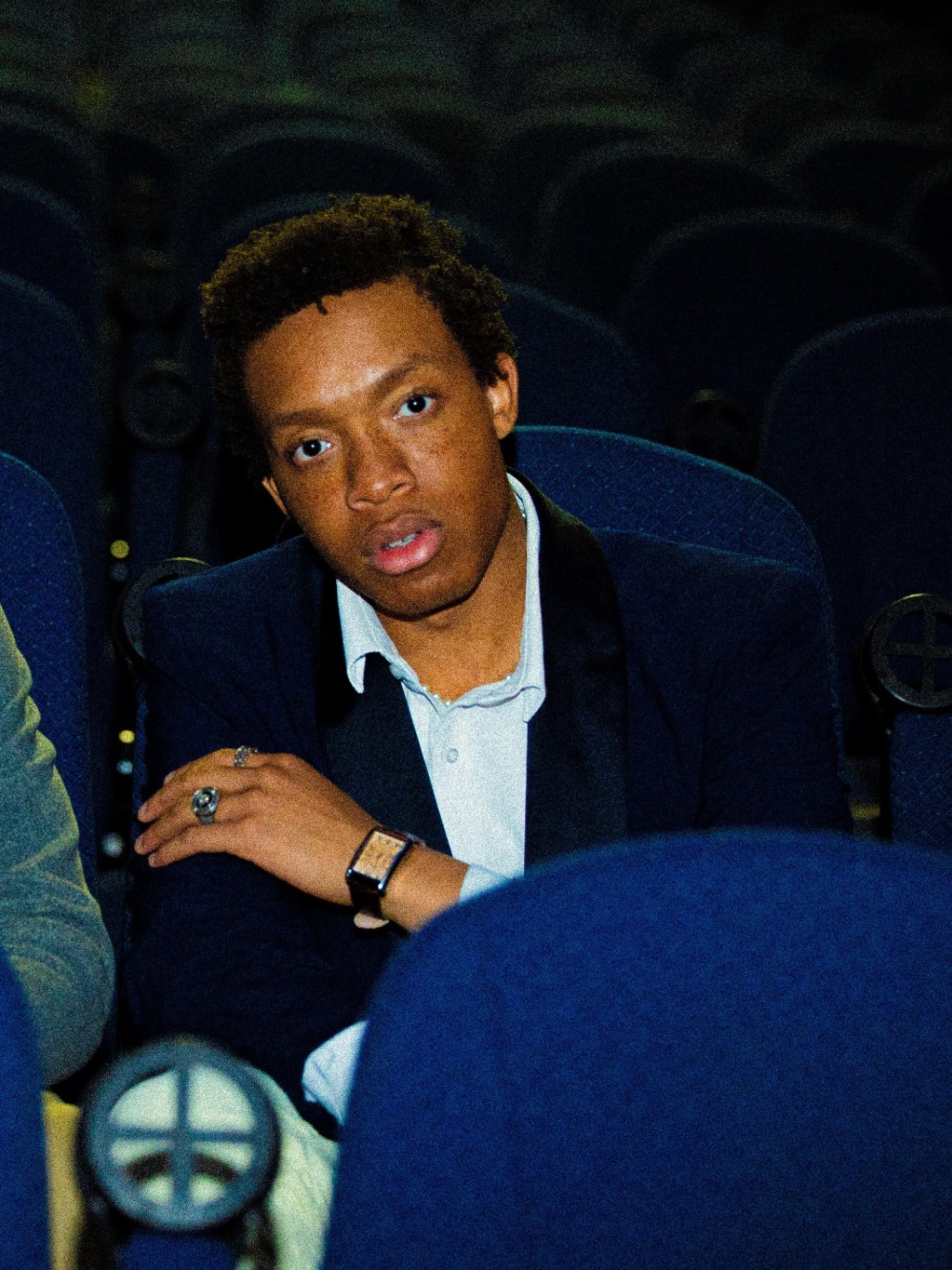 Student seated in a theater looking at camera 