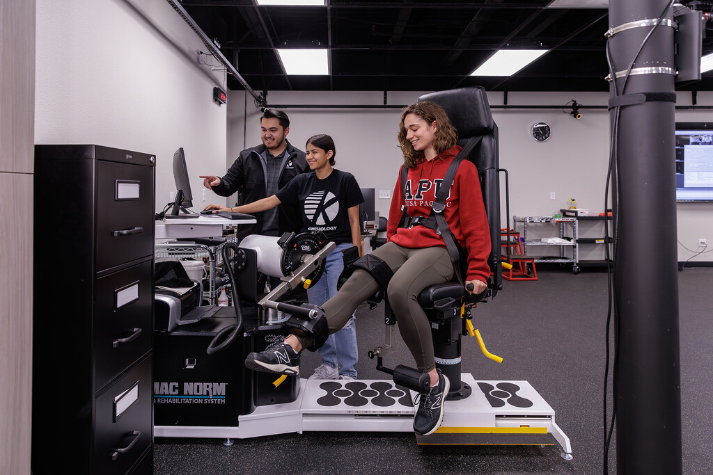 Woman uses rehabilitation machine as students watch