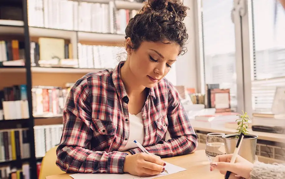 Prospective college student writing notes during a conversation at a table