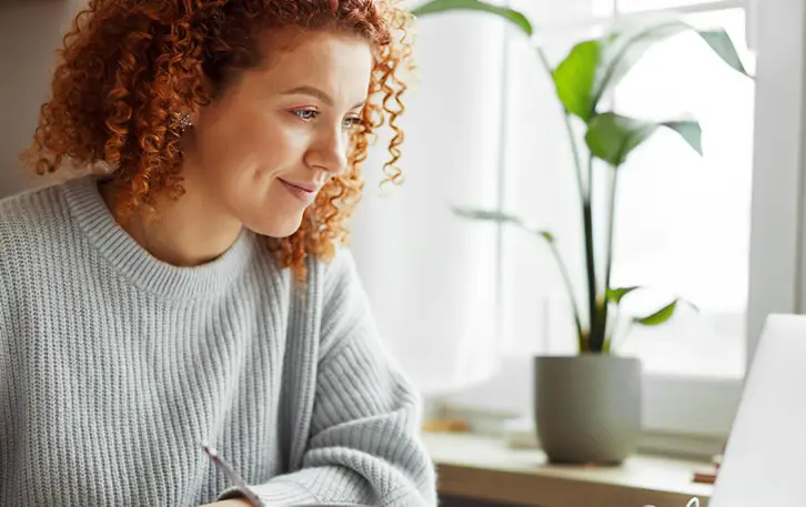 students looking at her computer with a plant in the background