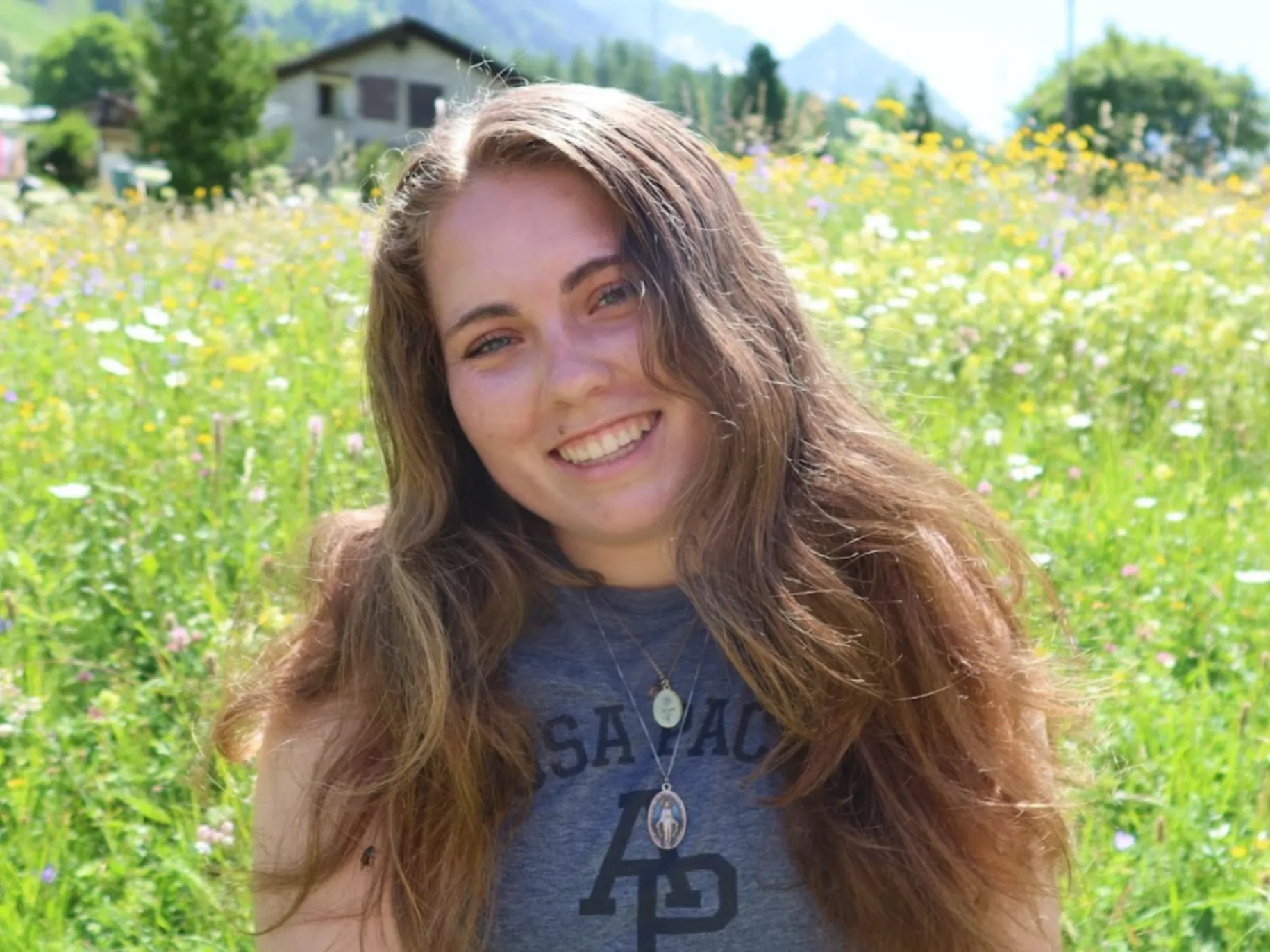 Zelie Ebiner ’26 in a flower field wearing APU merchandise.