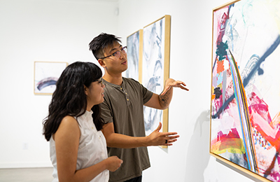 student and professional looking at canvas on the wall