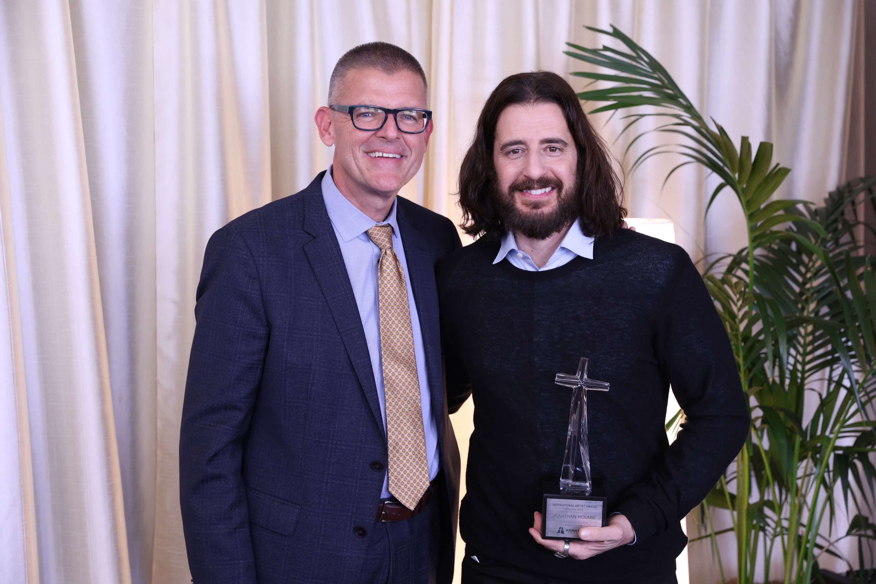 president morris with jonathan roumie holding an award