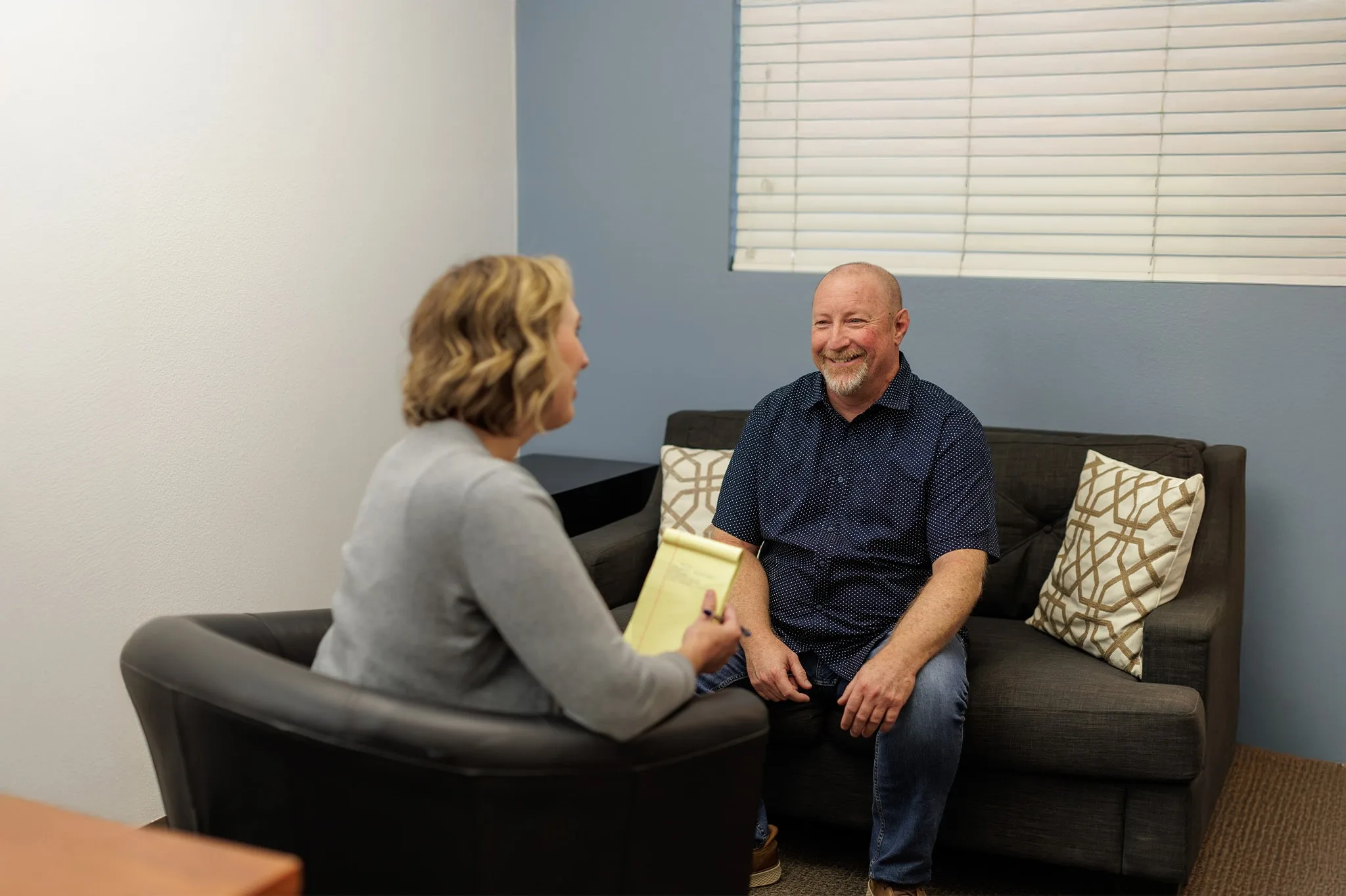 a man sitting on a couch speaking with counselor