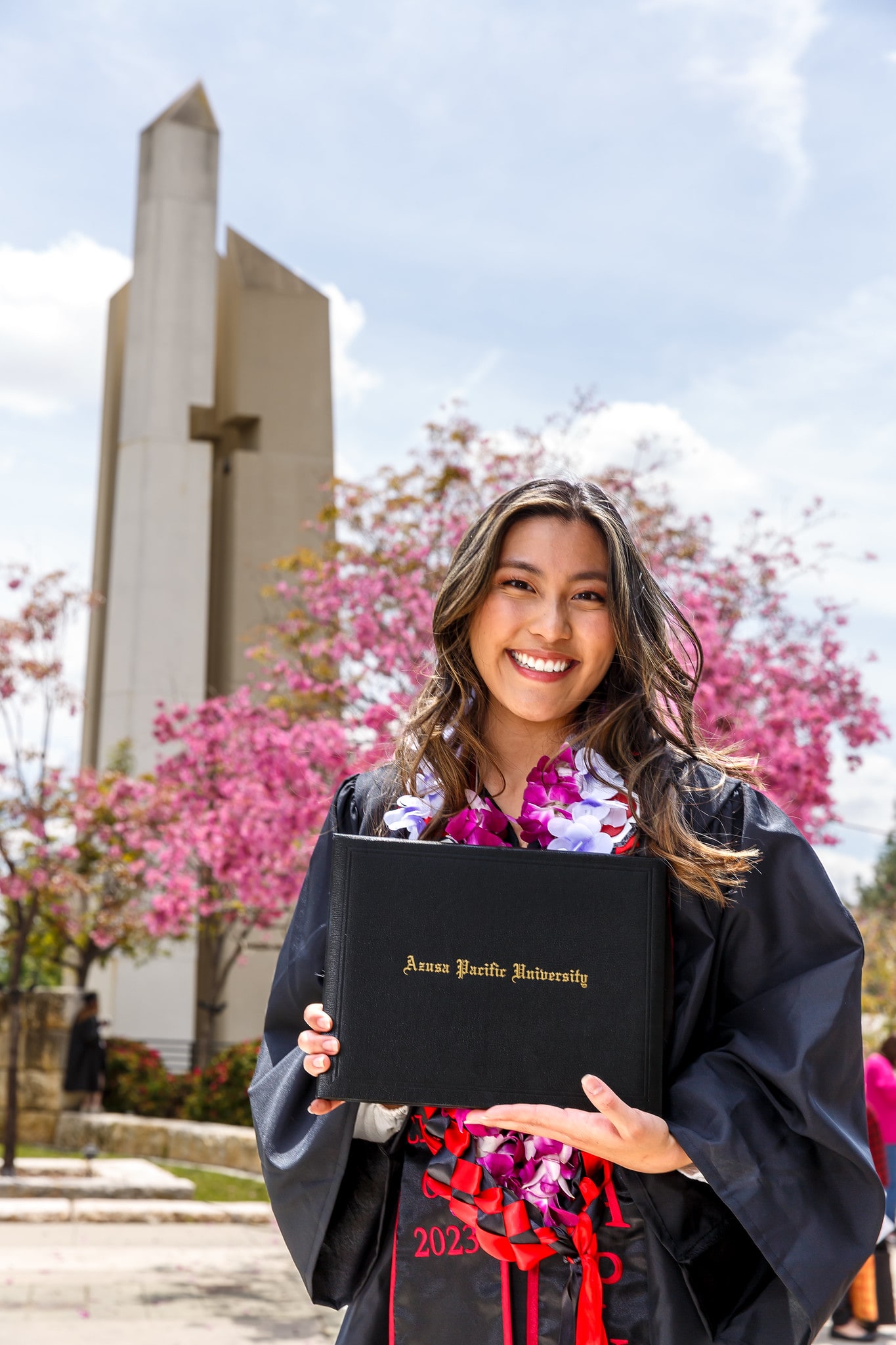 apu students wearing her cap and gown and holding her diploma.