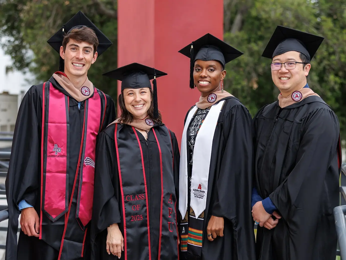 Four APU students smile together at commencement