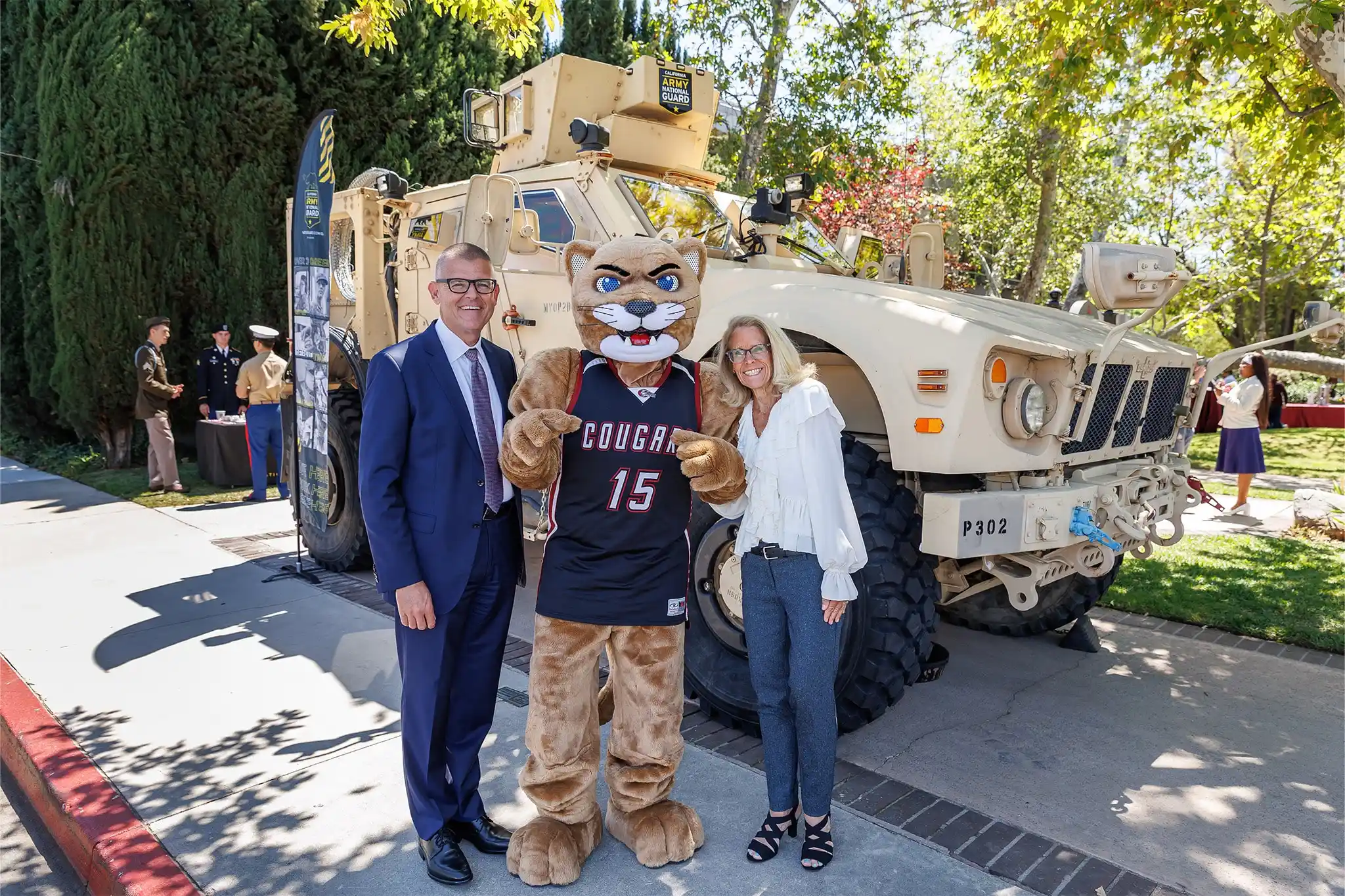 President Morris, Faythe, and Freddy standing in front of a tank