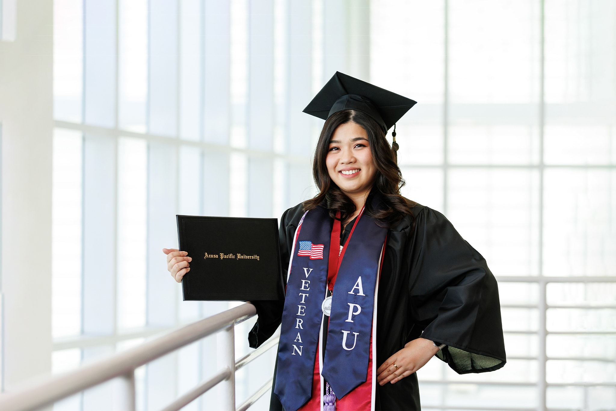 Student in cap and gown with Veteran sash