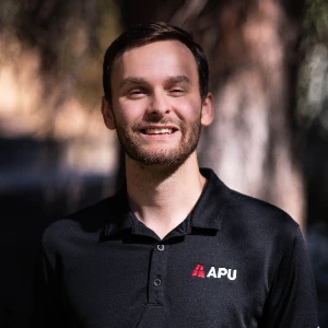 Selby wearing a black polo shirt and smiling