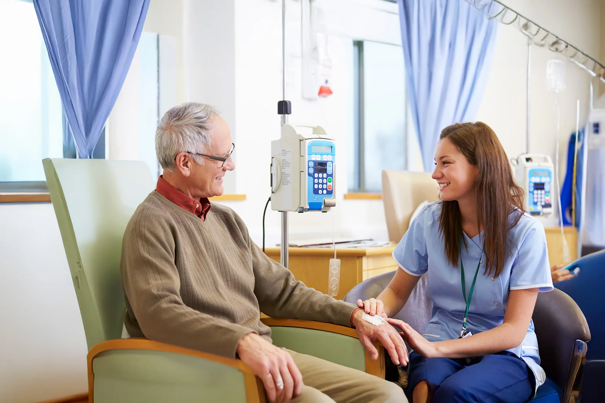 nursing students in brick red taking blood pressure of another student with their instructor guiding them