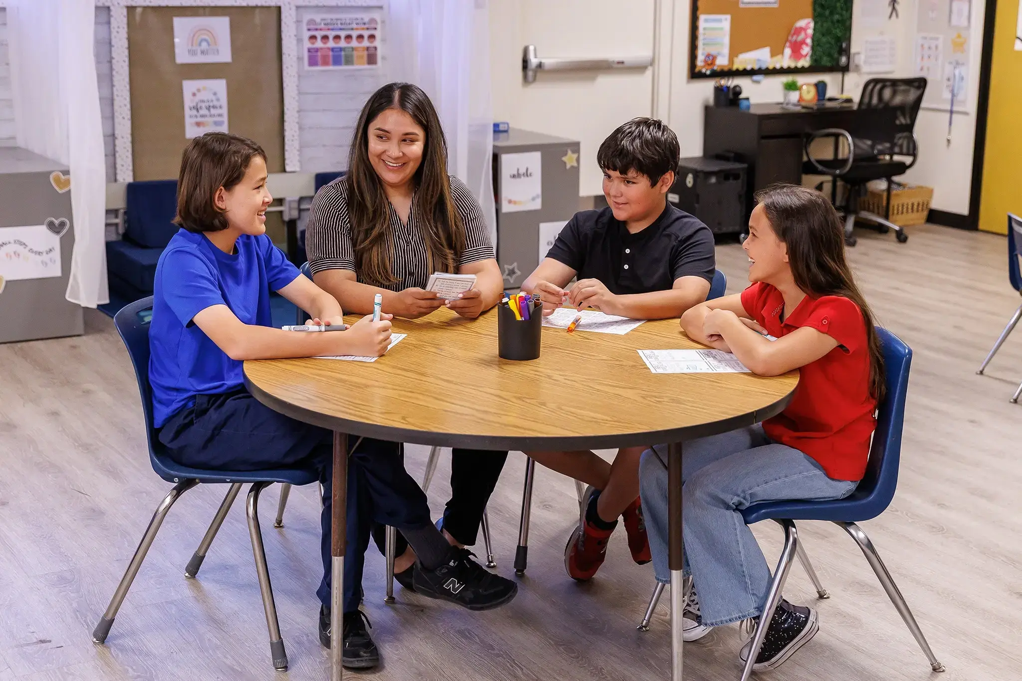 Teacher works with three elementary students during a small-group classroom activity.