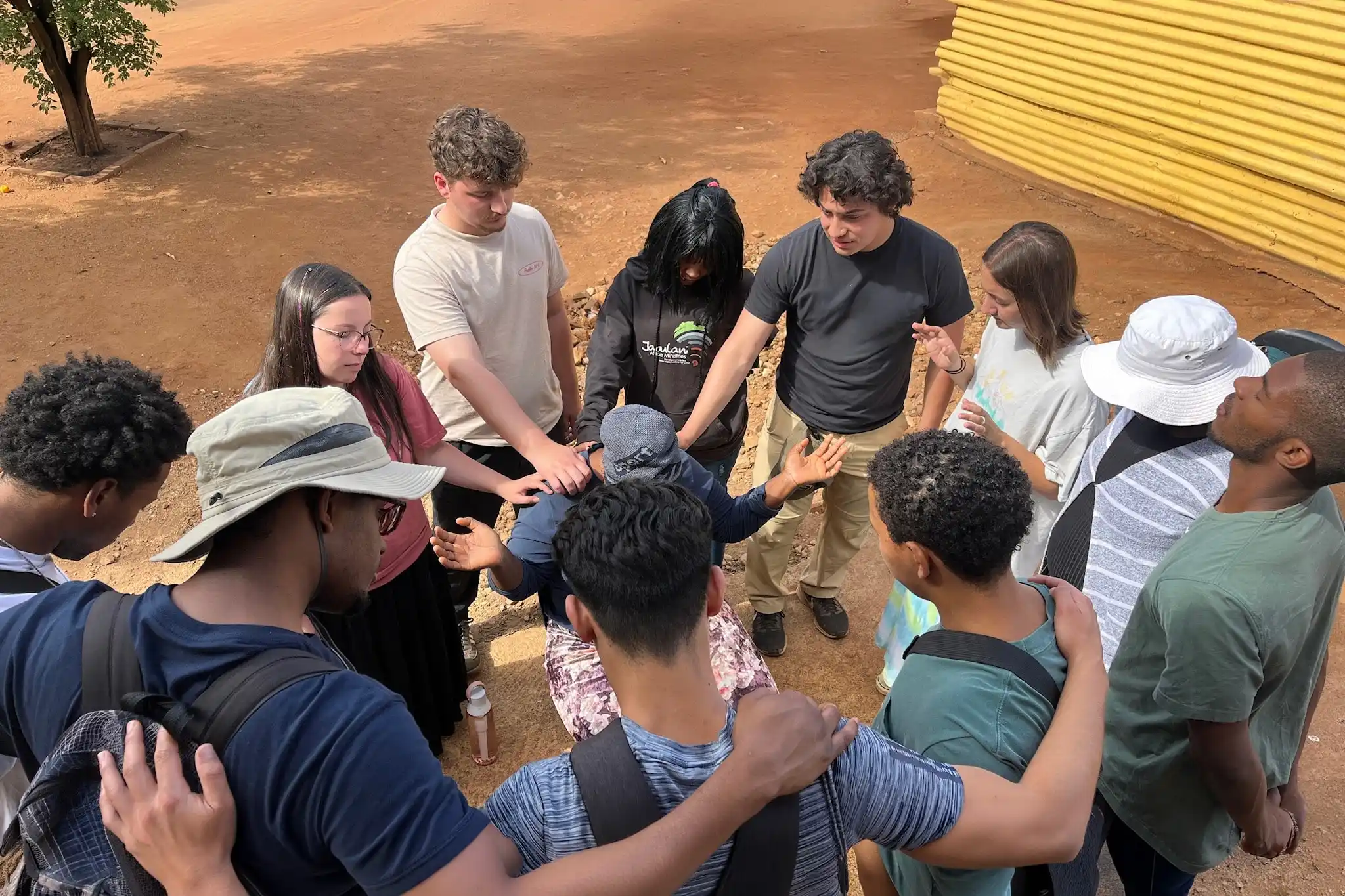 students in a cyrcle praying for a person