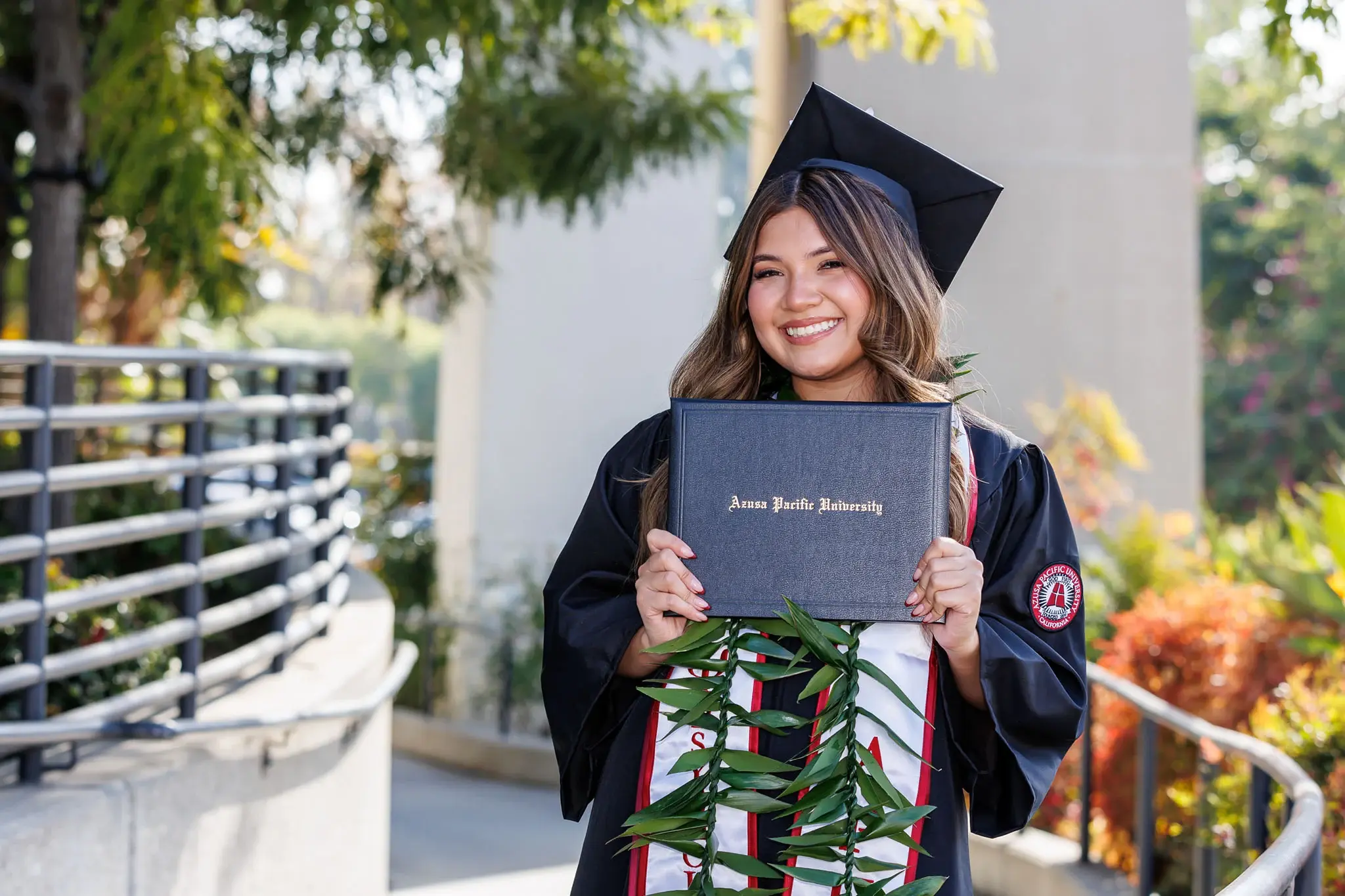 female student wearing cap and gown and holding her diploma