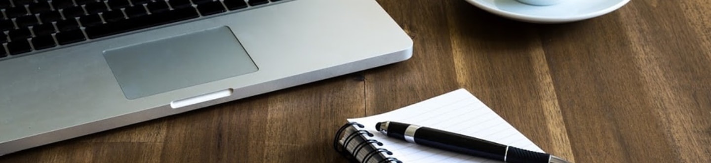 a laptop and a pen on top of a notebook